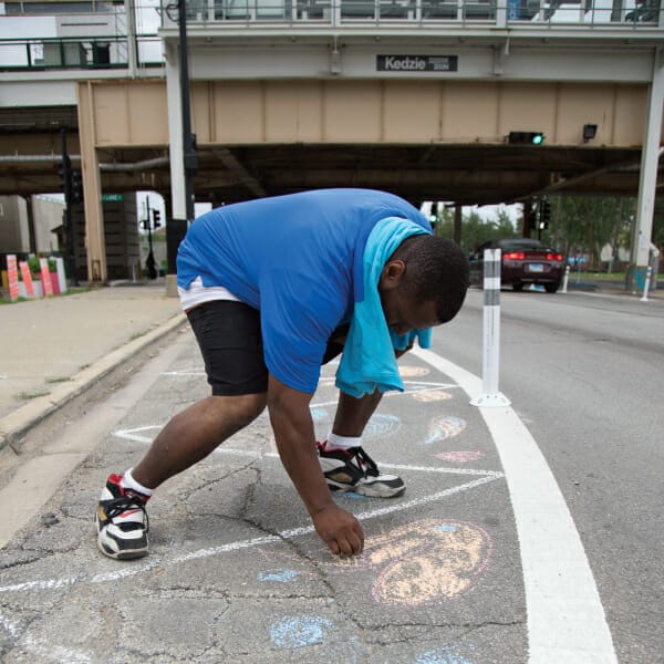 Youth making chalk art in a sidewalk bumpout next to the Kedzie station